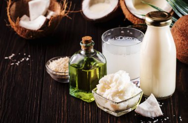Coconuts products - mct butter, oil, milk, oil, shavings on wooden background. Copy space. Hair, skin and body treatment concept