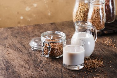 Vegan Buckwheat plant based milk in bottles, closeup, brown background. Non dairy alternative milk. Healthy vegetarian food and drink concept. Copy space
