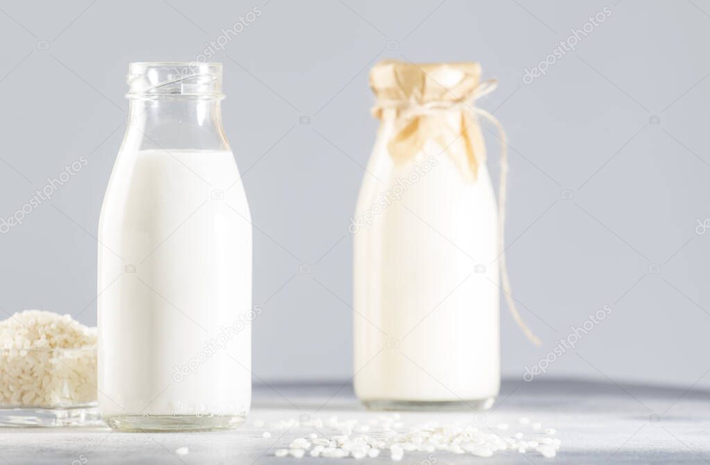 Vegan rice plant based milk in bottles, closeup, gray background. Non dairy alternative milk. Healthy vegetarian food and drink concept. Copy space