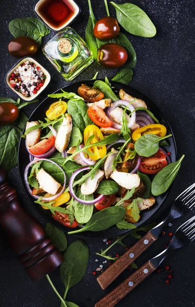 ほうれん草と春のサラダ グリルチキン チェリートマト アルグラ コーンサラダと赤玉ねぎ 健康食品の概念 黒い石のテーブル 最上階だ スペースのコピー — ストック写真