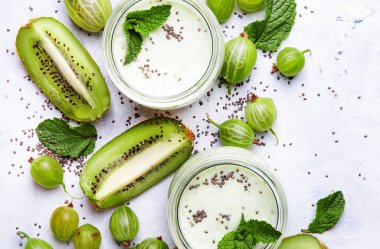 Bektaşi üzümünden meyve suyu ve milkshake, kivi ve yoğurtlu süt kokteyli? Chia tohumları, gri mutfak masası arka planı, düz yatak, üst görünüm