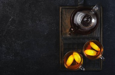 Zencefil, bal, limon ve adaçayı ile şifalı bitkisel çay. Bağışıklık güçlendirici, arka planda siyah mutfak masasında cam bardakta fotokopi alanı olan bir içecek. Üst görünüm