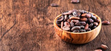 Ahşap arka planda soyulmamış kakao çekirdeği, yakın plan. Boşluğu kopyala