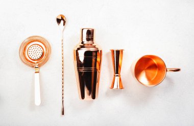 Kokteyl yapmak için bakır bar aletleri ve aksesuarları. Titretici, jigger, süzgeç, kaşık, maşa, muddler. Alkol ve içecek hazırlama konsepti. Beyaz arkaplan, üst görünüm, kopyalama alanı