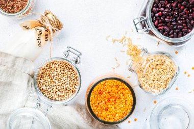 Sıfır israf ve sürdürülebilir yaşam tarzı. Plastiksiz depolama ve pişirme konsepti. Çeşitli organik süper yiyecekler, fasulyeler, tahıllar, tahıllar, baklagiller, yeniden kullanılabilir kutular ve kavanozlardaki tohumlar. Üst görünümü kopyala. Beyaz arkaplan