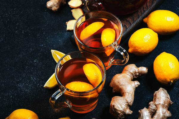 Healing black herbal tea with ginger, honey, lemon and sage. Immune booster drink in glass cup on black kitchen table background with copy space. Top view