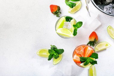 Limon, nane, çilek ve beyaz arka planda buzlu taze Mojito kokteyli. Yaz aylarında alkolsüz içecekler, içecekler ve kokteyller. Bar aletleri. Uzayı kopyala Üst görünüm