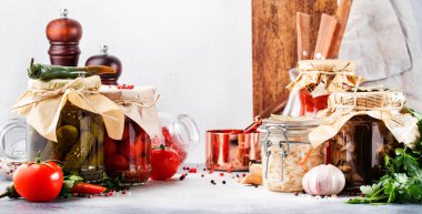 Konserve gıda konsepti. Mayalanmış, turşulu, marine edilmiş vejetaryen yemeği. Baharatlı kavanozlarda organik sebzeler ve meyveler ve beyaz mutfaktaki otlar. Ev yapımı kurnazlık.