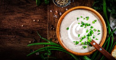 Kırsal ahşap zemin üzerinde kızarmış ekmek ve soğanlı kremalı mantar çorbası.