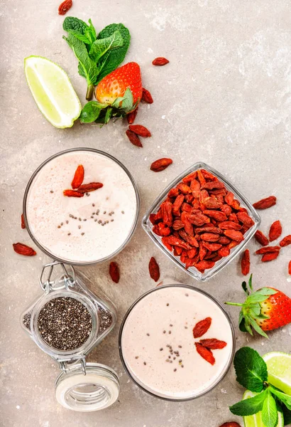 Healthy blended drink. Organic vegan non dairy smoothie with strawberry and goji berries, chia seeds and lime. Gray background with copy space. Top view