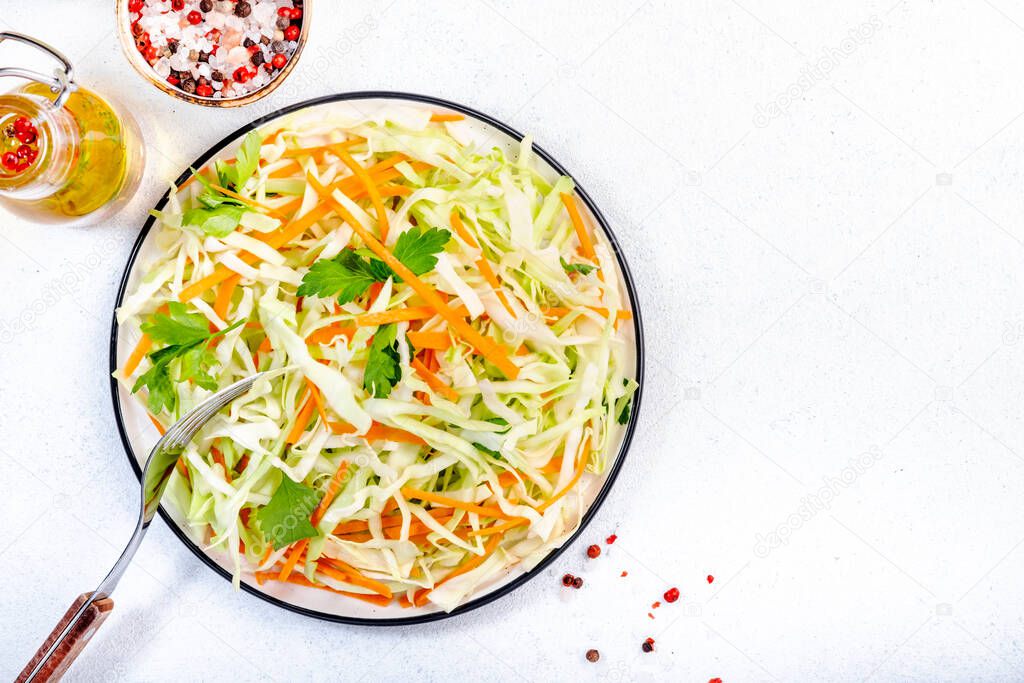 White cabbage salad coleslaw with carrot on white kitchen table background. Top view, copy space