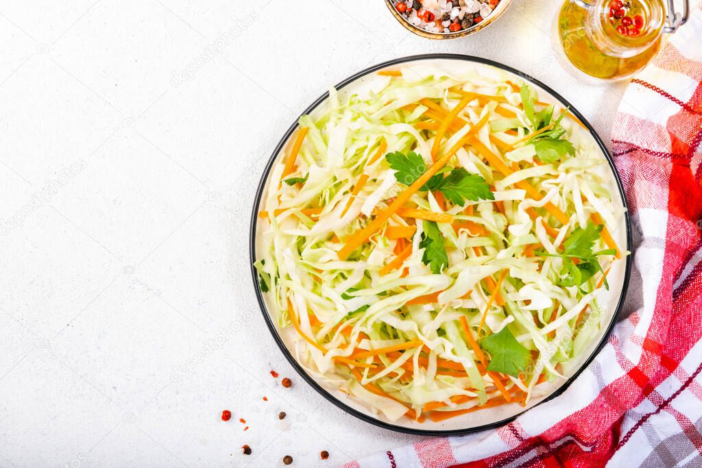 White cabbage salad coleslaw with carrot on white kitchen table background. Top view, copy space