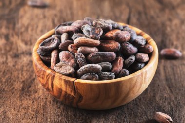 Ahşap arka planda soyulmamış kakao çekirdeği, yakın plan. Boşluğu kopyala