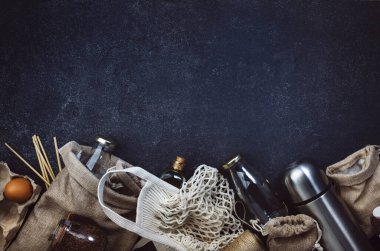 Sıfır atık, plastiksiz ve sürdürülebilir yaşam tarzı konsepti. Geri dönüşümlü, yeniden kullanılabilir çevre dostu çantalar, paket, şişe, kutu ve konteynırlar, ağ torbası. Siyah arkaplan, boşluk kopyala, üst görünüm