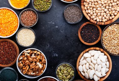 Süper yiyecekler, baklagiller, fındıklar, tohumlar ve tahıllar gri arka plandaki kaselerde seçiliyor. Chia, spirulina, fasulye, goji üzümü, kinoa, zerdeçal, mung fasülyesi, karabuğday, mercimek, keten tohumu, yabani pirinç ve badem gibi süper yiyecekler. Boşluğu kopyala, üst görünüm