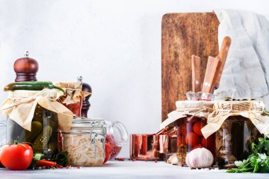 Konserve gıda konsepti. Mayalanmış, turşulu, marine edilmiş vejetaryen yemeği. Baharatlı kavanozlarda organik sebzeler ve meyveler ve beyaz mutfaktaki otlar. Ev yapımı kurnazlık.