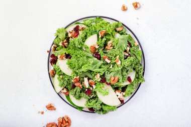 Kurutulmuş yaban mersinli lahana salatası, yeşil elma ve ceviz. Sağlıklı vejetaryen yemeği, üst manzara, gri mutfak masası arka planı.