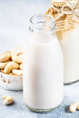 Biberonlu vejetaryen fındık sütü, yakın plan, beyaz masa arka planı. Sütsüz alternatif süt. Sağlıklı vejetaryen yiyecek ve içecek konsepti. Boşluğu kopyala