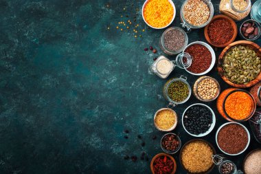 Sıfır israf ve sürdürülebilir yaşam tarzı. Plastiksiz depolama ve pişirme konsepti. Çeşitli organik süper yiyecekler, fasulyeler, tahıllar, tahıllar, baklagiller, yeniden kullanılabilir kutular ve kavanozlardaki tohumlar. Üst görünümü kopyala. Koyu arkaplan