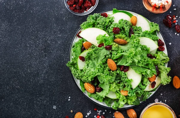 Kale salad with dried cranberry, green apples and almonds. Healthy vegan food, top view, black kitchen table background — Stock Image Kale Salad Dried Cranberry Green Apples Almonds Healthy Vegan Food Royalty Free Stock Photos