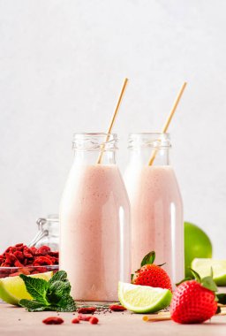 Sağlıklı harmanlanmış süper yiyecek içeceği. Çilekli, goji üzümlü, chia tohumlu ve limonlu organik diyet smoothie. Eko fendley pipetli cam şişeler. Kopyalama alanı olan gri arkaplan