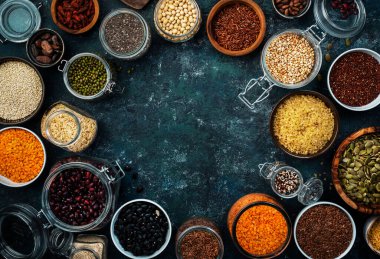 Sıfır israf ve sürdürülebilir yaşam tarzı. Plastiksiz depolama ve pişirme konsepti. Çeşitli organik süper yiyecekler, fasulyeler, tahıllar, tahıllar, baklagiller, yeniden kullanılabilir kutular ve kavanozlardaki tohumlar. Üst görünümü kopyala. Koyu arkaplan