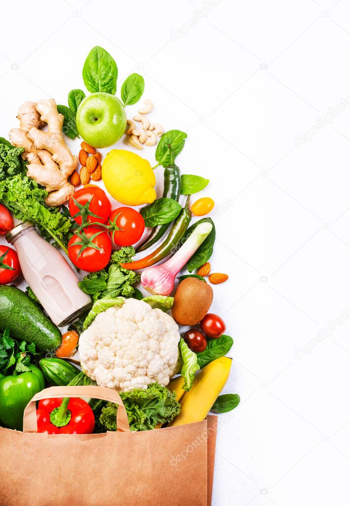 Healthy vegan vegetarian food in full paper bag, vegetables and fruits on white background, copy space, banner. Shopping food supermarket, groceries and clean eating concept. Healthy food background