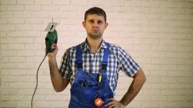 Bir elektrikli testere olan adam. Marangoz bir elektrikli araç ile çalışır. Usta, profesyonel bir tamirci. Adam elinde bir elektrikli testere tutuyor..