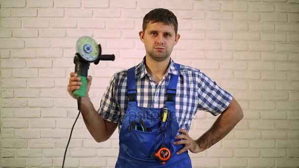 En man med en vinkelslip. Reparatör, master professional. Man håller i sin hand elektriska verktyg. En arbetstagare med en vinkelslip. — Stockvideo