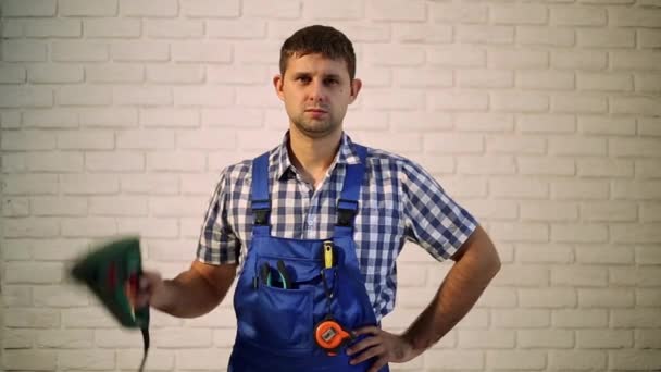 Un hombre con un perforador. Maestro constructor, reparador de herramientas. El hombre con el taladro en el fondo de la pared de ladrillo. Trabajando, martillo, taladro, perforador . — Vídeos de Stock