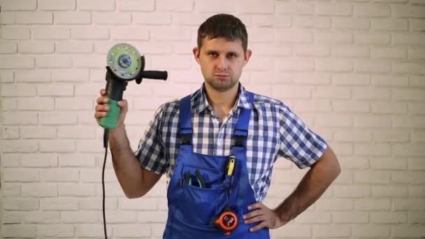 Repairman, master professional. A worker with an angle grinder. A man with an angle grinder. Man holds in his hand electric tool. — Stock Video