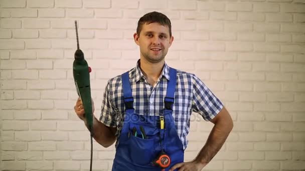 Een man met een perforator. De man met de boor op de bakstenen muur achtergrond. Werken, hamer, boor. Bouwmeester, reparateur gereedschap. — Stockvideo