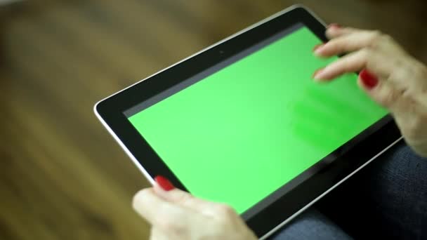 Uma mulher segura um tablet com uma tela verde. Os dedos femininos seguram o comprimido. Computador tablet com tela verde para o seu conteúdo . — Vídeo de Stock