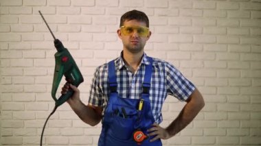 Bir perforator olan bir adam. İnşaat işçisi çekiç ile. Tuğla duvar arka plan üzerinde bir matkap ile çalışma.