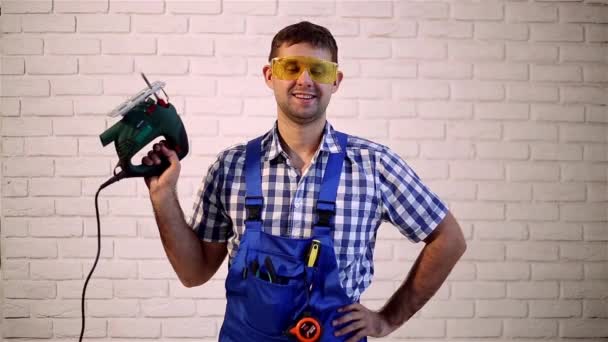 Un hombre con una sierra eléctrica. Trabajando con sierra eléctrica. Trabajador de la construcción con una herramienta eléctrica . — Vídeo de stock