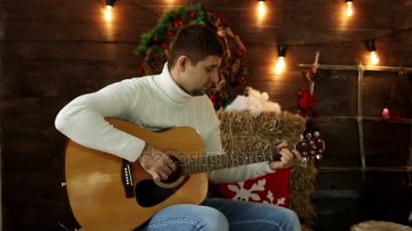 Adam bir Noel arka plan üzerinde gitar çalmak. Adam gitar çalmak.
