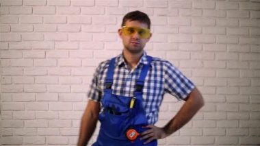 Adam onarım yapar. Bir tornavida olan bir adam. Elektrikli el aletleri olan adam. Tornavida ile inşaat işçisi. Bir erkekte iş elbiseleri.