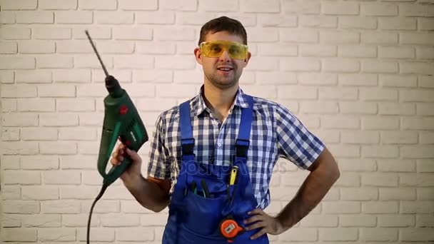 Trabajando con un taladro en el fondo de la pared de ladrillo. Un hombre con un perforador. Obrero de la construcción con martillo. El hombre hace reparaciones . — Vídeos de Stock