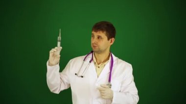 Doktor yeşil bir arka plan üzerinde bir şırınga. Doktor enjekte etmeye hazırlanıyor. Doktor bir şırınga tutuyor.