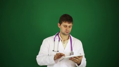 Beyaz önlük erkek doktor. Doktor bir tablet bilgisayar ile. Modern tıp, cerrah, tedavi, yeni teknolojileri. Doktor yeşil bir arka plan üzerinde.