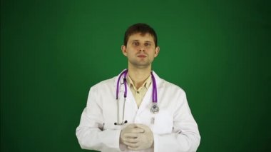 Yeşil bir arka plan üzerinde erkek doktor. Doktor vasıl belgili tanımlık perde işaret ediyor. Tıp, sağlık ve genç bir doktor.