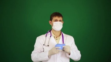 Bir doktor maskeli lavman tutar. Yeşil zemin üzerine Beyaz önlük doktor. Doktor lavman ile.
