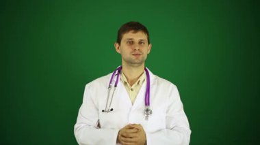 Genç bir dostu doktor. Yeşil bir arka plan üzerinde ciddi doktor. Beyaz bir ceket, bir terapist, bir cerrah doktor.