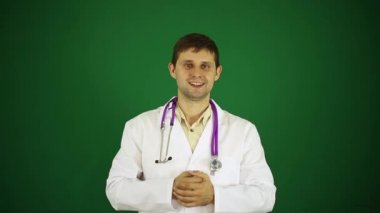 Doktor yeşil arka plan üzerinde nesne üzerinde gösterir. Genç bir dostu doktor. Beyaz önlük içinde erkek doktor. 