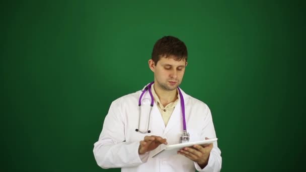 白衣の男性医師。タブレット コンピューターでは医者。現代医学、外科医、治療法、新技術。緑の背景に医師. — ストック動画