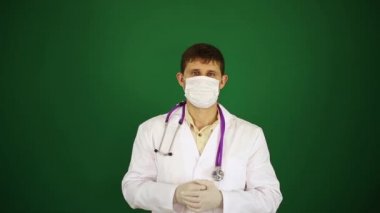 Maske yeşil bir arka plan üzerinde doktor. Doktor eliyle bir işareti yapar. Terapist, sargı bezi cerrah.