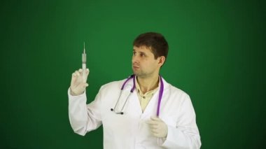 Yeşil zemin üzerine şırınga ile genç doktor. Tedavi, şırınga ve Beyaz önlük doktor. Doktor enjekte önermez. Doktor enjeksiyonlari korkuyor.