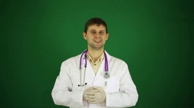 Doktor bir parmak kameraya çekiyor. Yeşil bir arka plan üzerinde erkek bir doktor. Pozitif genç doktor.