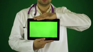 Doktor bir tablet bilgisayar ile. Yeşil bir arka plan üzerine doktor. Doktor bir tablet bilgisayar tutuyor.