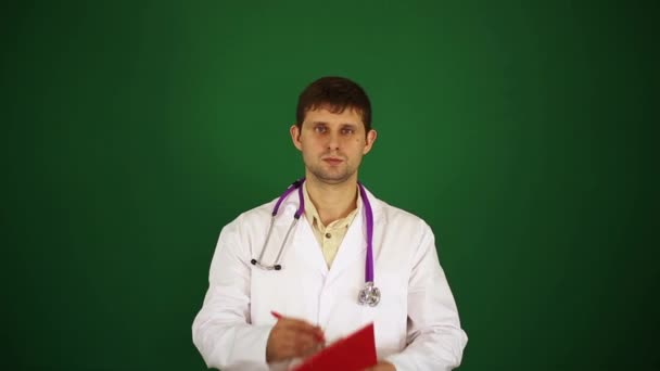 Doutor em um fundo verde escreve em um bloco de notas. Médico de jaleco branco. O médico escreve o historial médico. Recepção no médico, médico, terapeuta . — Vídeo de Stock